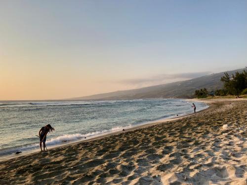 two people standing on a beach near the water at Villa Pwintosel 1, calme et confort à 300m de l'océan in Saint-Leu