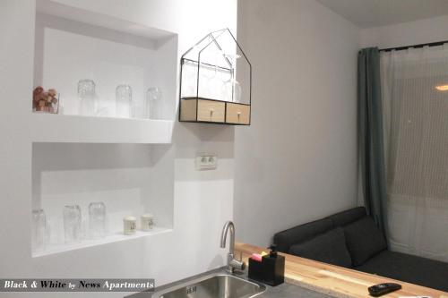 a kitchen with a sink and a shelf with glasses at Black & White - News Apartment in Bucharest