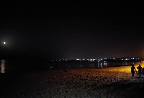 two people walking on the beach at night at New Summer Apartment in Agnone Bagni