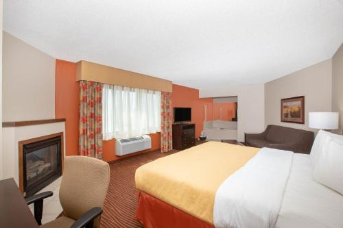 a hotel room with a bed and a fireplace at AmericInn by Wyndham Muscatine in Muscatine