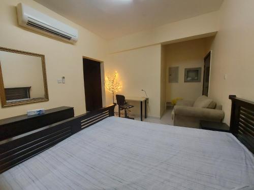 1 dormitorio con cama con espejo y sofá en Nice studio for stay .., en Al Ain
