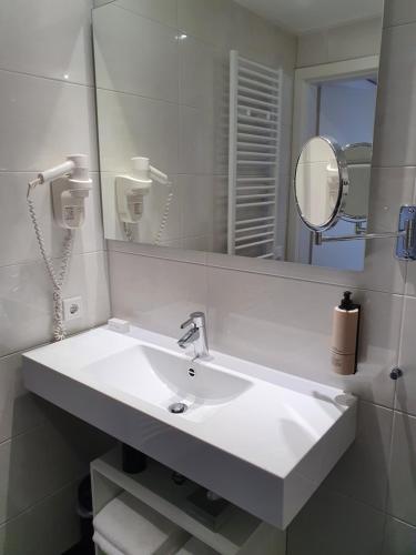 
a white sink sitting under a mirror in a bathroom at Badhotel Bruin in Oost-Vlieland
