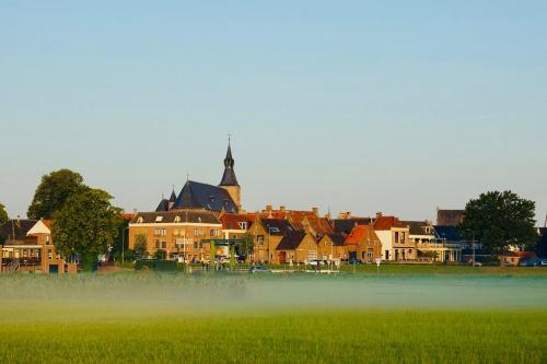 a town with a field of grass and a church at Aparthotel Hattem in Hattem