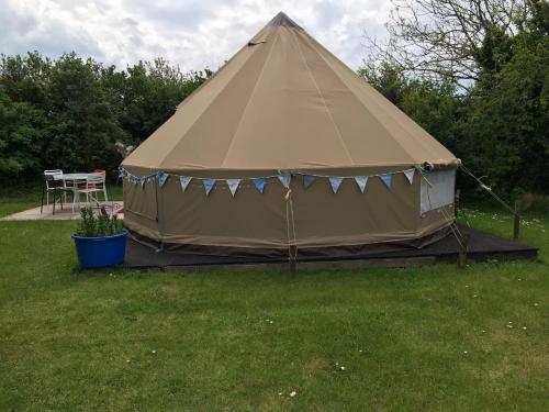 a large tan tent in a yard with a table at Coutts Glamping in Wadebridge