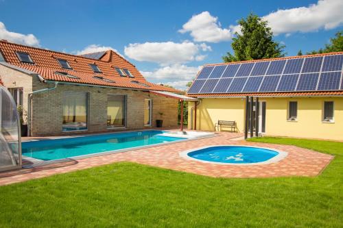 a house with a swimming pool with solar panels on the roof at Ponty-Lak Panzió in Dávod