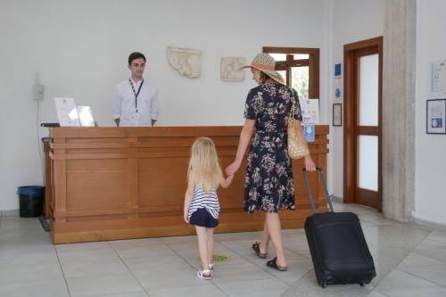 una mujer sosteniendo la mano de una niña con una maleta en Xenia Ouranoupolis, en Ouranoupoli