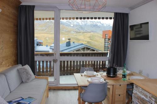 un salon avec un canapé et une grande fenêtre dans l'établissement Lac du Lou Appartements VTI, à Val Thorens