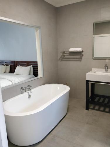 a white bathroom with a tub and a sink at Lake Kariba Inns in Siavonga