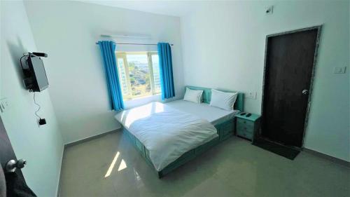 1 dormitorio con 1 cama con cortinas azules y ventana en SHIKHAR BUNGLOW - A Stunning Valley View Bungalow in Mount Abu, en Mount Abu