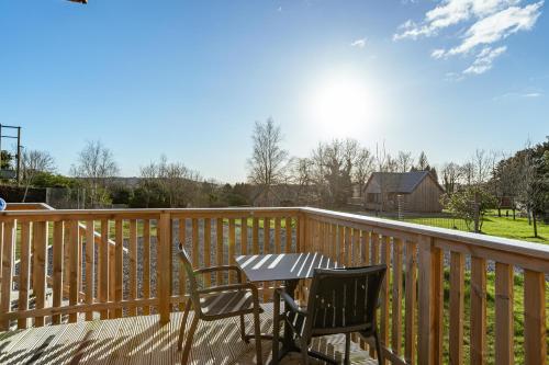 a table and chairs on a wooden deck at Kestrel Lodge 7 with Hot Tub in Newton Stewart