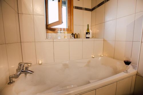 une baignoire blanche avec un verre de vin dans l'établissement Ferme A Jules - Stunning Farmhouse sleeps up to 26, à Montriond
