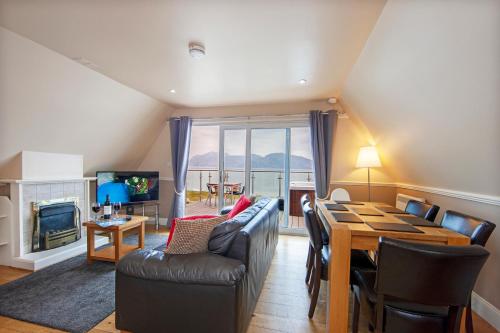 ein Wohnzimmer mit einem Tisch, Stühlen und einem TV in der Unterkunft Loch Linnhe Waterfront Lodges with Hot Tubs in Glencoe