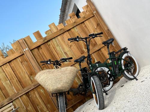 dos bicicletas estacionadas junto a una valla de madera en Maisonnette à proximité plage et port de St-Martin, en Saint-Martin-de-Ré