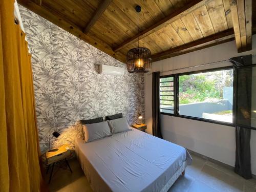 a bedroom with a bed and a large window at villa Pwintosel 2 in Saint-Leu