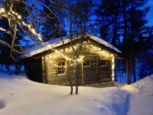 une cabane en rondins avec des lumières dans la neige dans l'établissement Kuukkeli Log Houses Aurora Cabin - Jaspis, à Saariselka