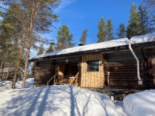 une cabane en rondins avec un toit enneigé dans la neige dans l'établissement Kuukkeli Log Houses Aurora Cabin - Jaspis, à Saariselka