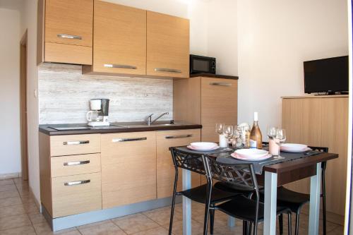 - une cuisine avec une table, des chaises et des verres à vin dans l'établissement Terres de France - Les Hauts du Maquis, à Linguizzetta