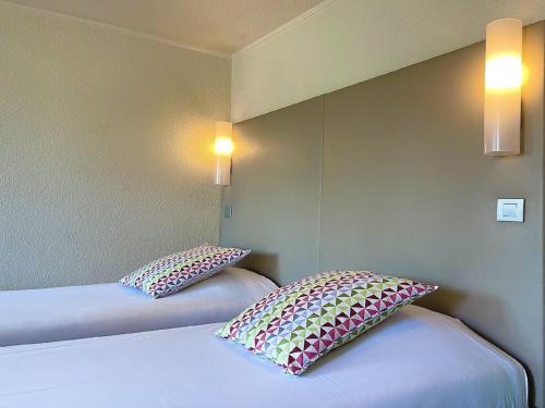 two beds in a room with two pillows on them at Campanile Arras - Saint-Nicolas in Saint-Nicolas