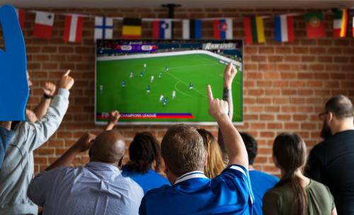 a group of people watching a soccer game on a screen at Campanile Arras - Saint-Nicolas in Saint-Nicolas