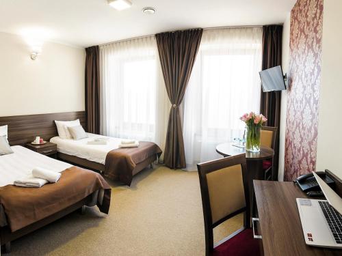 オシフィエンチムにあるHotel Dąbrowskiのベッド2台とデスクが備わるホテルルームです。