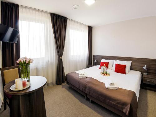 オシフィエンチムにあるHotel Dąbrowskiのベッドと花のテーブルが備わるホテルルームです。
