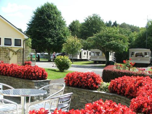 a table and chairs in a garden with red flowers at Flemings White Bridge Self-Catering Mobile Home Hire in Killarney