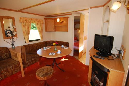 a living room with a table and a tv at Flemings White Bridge Self-Catering Mobile Home Hire in Killarney