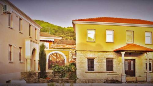 una casa amarilla con techo rojo junto a dos edificios en ΑΡΑΪΔΟΥ΄-ARAIDOY, en Ioannina