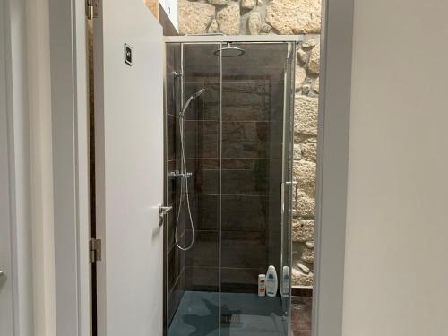 a bathroom with a walk in shower next to a stone wall at Campanhã Boutique Station in Porto