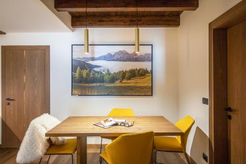 a dining room with a wooden table and yellow chairs at Cima Dodici B&B - Apartments in Sesto