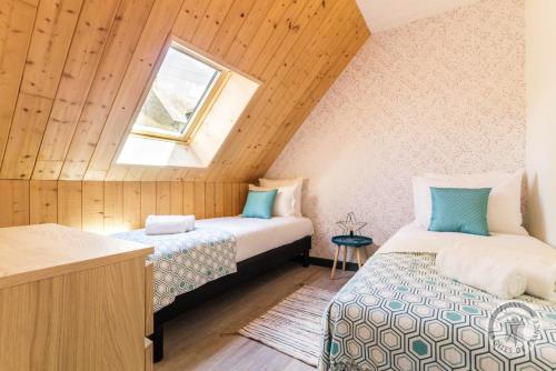 2 Betten in einem Dachzimmer mit Fenster in der Unterkunft Maison charmante à Pontorson avec piscine partagée in Pontorson