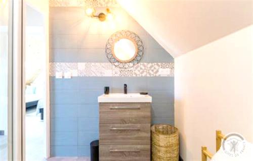 ein Badezimmer mit Waschbecken und Spiegel in der Unterkunft Maison charmante à Pontorson avec piscine partagée in Pontorson