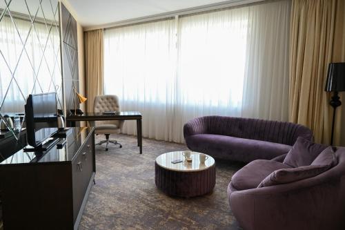 a living room with two purple couches and a television at Aleksandar Palace Hotel Congress Center & SPA in Skopje