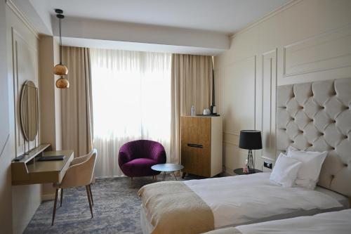 a hotel room with a bed and a desk and a window at Aleksandar Palace Hotel Congress Center & SPA in Skopje