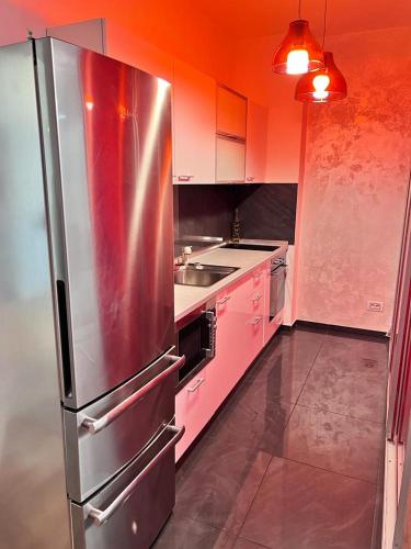 une cuisine avec des placards roses et un réfrigérateur en acier inoxydable dans l'établissement APARTAMENT LE MER TITEICA, à Floreasca