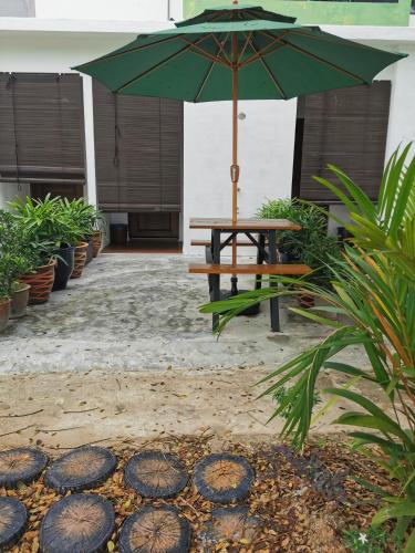 a picnic table with an umbrella in a courtyard at Tatami D'Tepi Laut - PANGKOR ISLAND in Pangkor