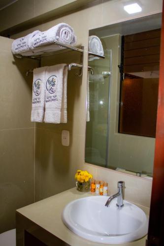 a bathroom with a sink and a mirror and towels at Hotel Tara Machupicchu in Machu Picchu