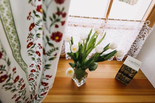 a vase of flowers on a table next to a window at Erzgebirgshaus Zirbenliebe in Kurort Altenberg
