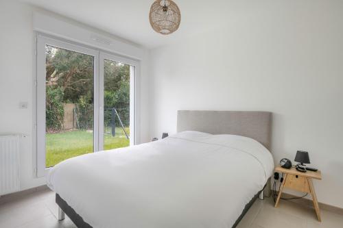 Un dormitorio blanco con una cama grande y una ventana en Appartement moderne pour 4 situe a La Baule Escoublac, en La Baule