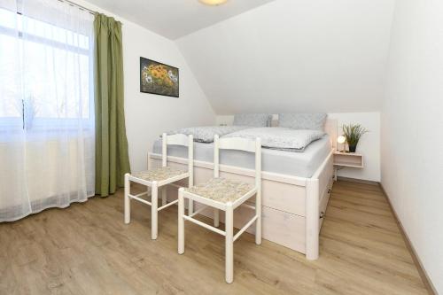 a small bedroom with a bed and two chairs at Ferienwohnungen im Haus Herrmann in Neuharlingersiel