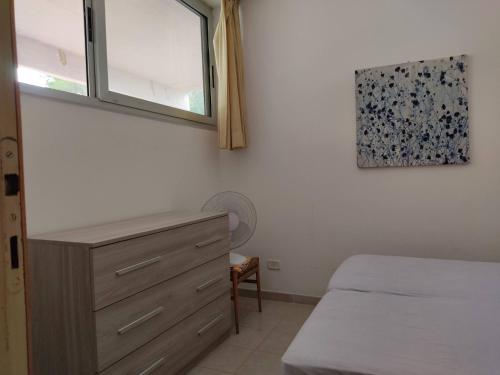 ein Schlafzimmer mit einem Bett, einer Kommode und einem Fenster in der Unterkunft Punta Ala Top apartment in Punta Ala