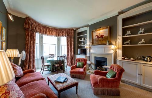 a living room with red chairs and a fireplace at The Jockey Club Rooms in Newmarket