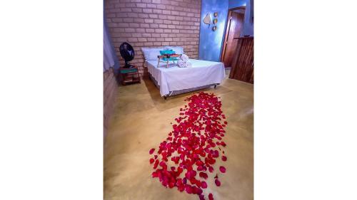 a pile of red petals on the floor next to a bed at Chalé 03 Itaipu Vale da Colina Niterói in Niterói