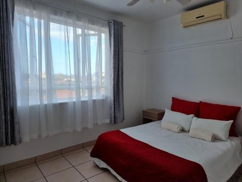 a bedroom with a red and white bed with a window at Frere Hill in Durban