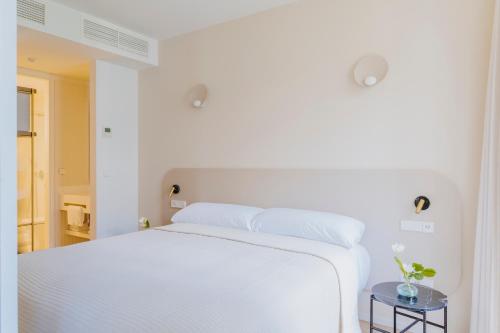 a white bedroom with a white bed and a table at The Passage Apartments in Donostia-San Sebastián