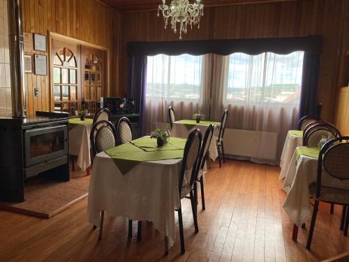 une salle à manger avec des tables et des chaises ainsi qu'un lustre dans l'établissement Hostal Maria, à Castro