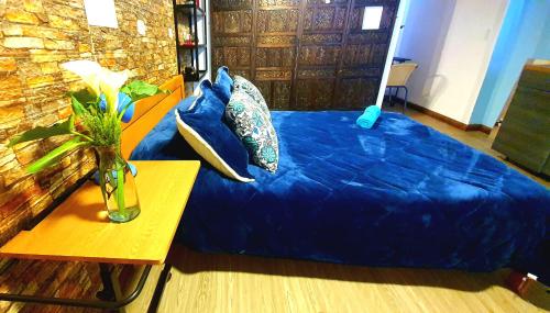a bed with blue sheets and a vase on a table at Aparta estudio Xenia in Bogotá