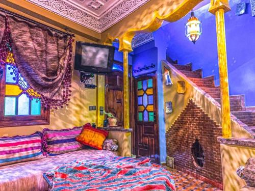 a bedroom with a bed and a tv and a staircase at Dar Lalla chafia 2 in Chefchaouene