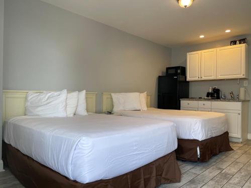 two beds in a hotel room with white sheets at Rio Motel and Suites in Wildwood