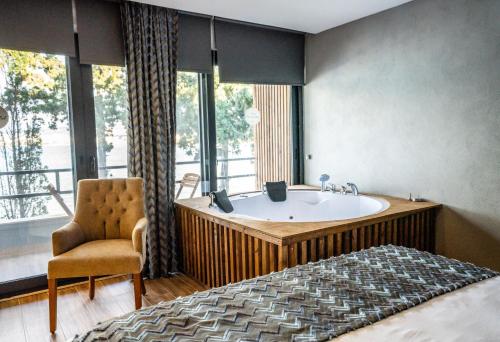 a bedroom with a tub and a bed and a chair at Sifne Thermal Otel in Çeşme
